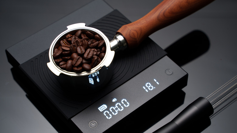 Coffee beans in a cup on a black scale