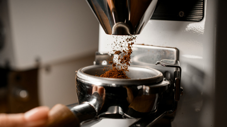 A closeup of a coffee grinder pouring grounds