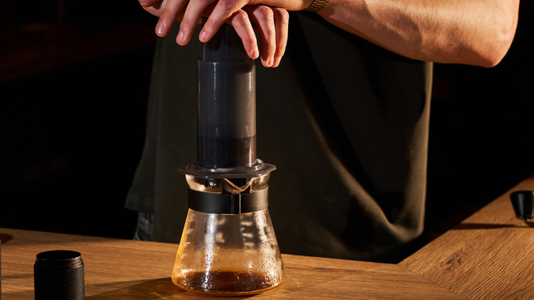 Hands pressing an AeroPress brewer, to create coffee