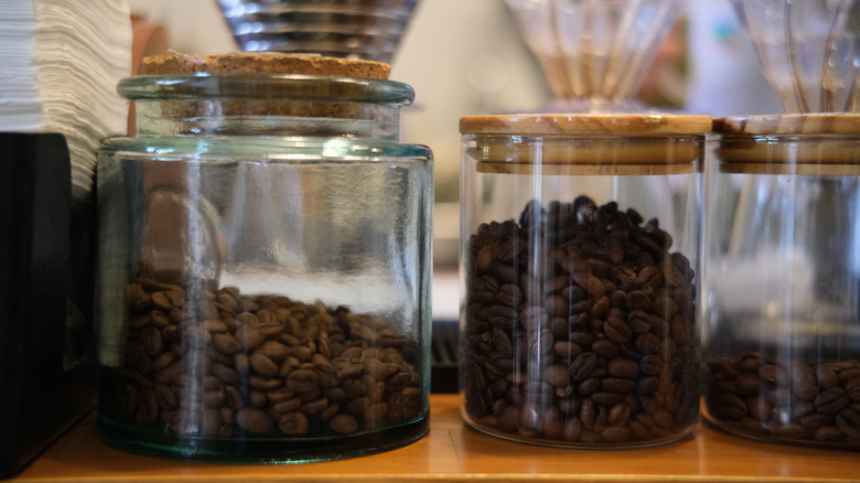 Three glass jars of coffee beans on a wooden table