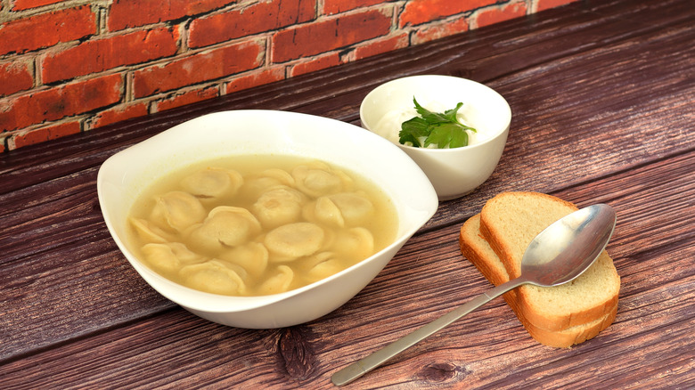 A bowl of freshly cooked dumplings with broth and bread