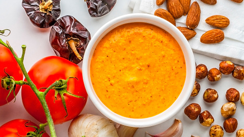 Romesco sauce in a bowl with dried peppers, almonds, hazelnuts, garlic, and tomato