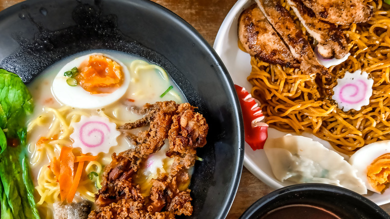 Bowl of ramen with fried chicken, narutomaki, egg, and miso soup served alongside yakisoba noodles and gyoza dumpling
