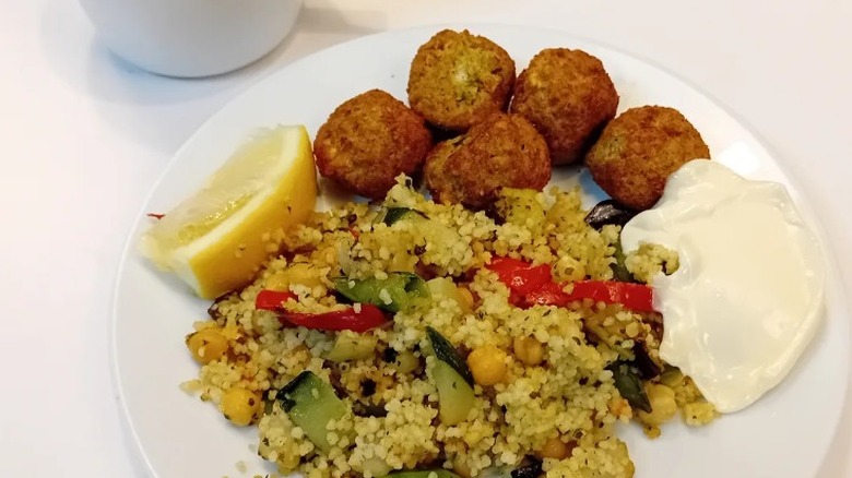 IKEA falafel meatballs with couscous and aioli on a white plate next to a white coffee cup