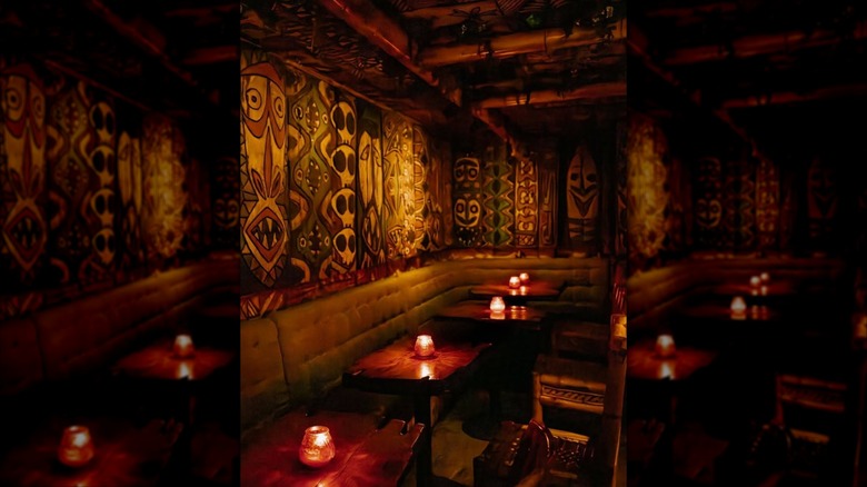 False Idol Speakeasy Dining room nook interior with tiki decor and booth seating, low lighting