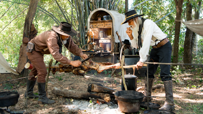 Cowboys preparing food and eating near a chuckwagon