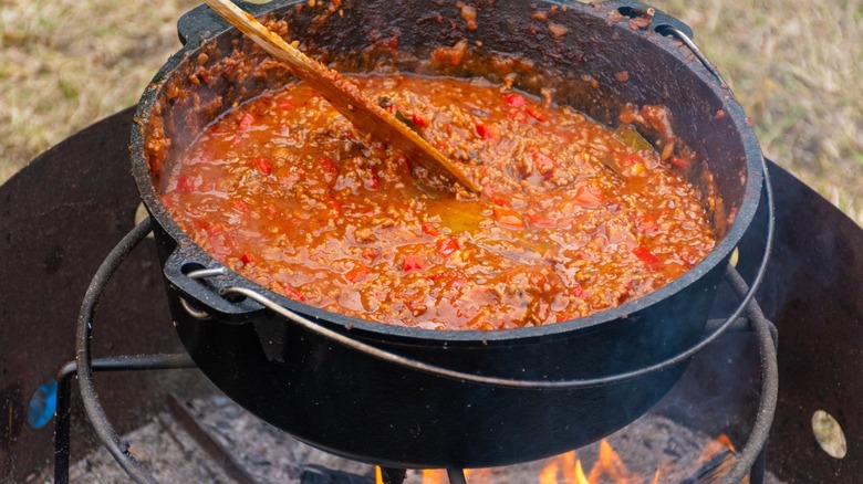 Chili in a cast iron cooking pot, stirred with a wooden spoon