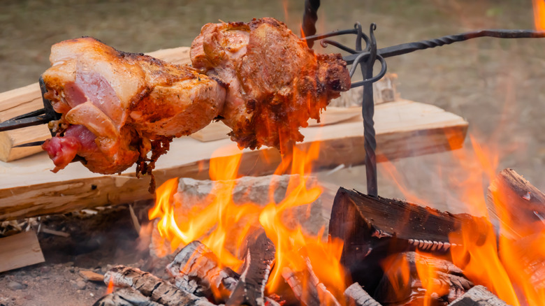 Cooking large meat peaces on spit over open fire at a historical festival