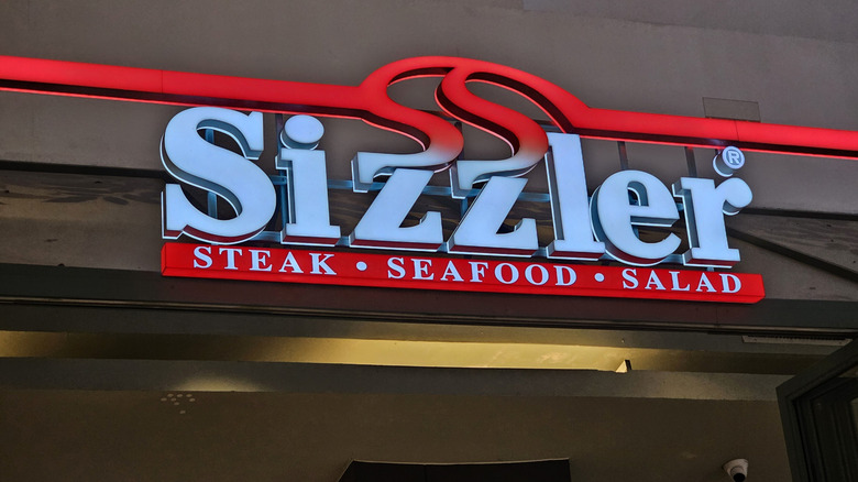 Sizzler sign lit up on front of restaurant