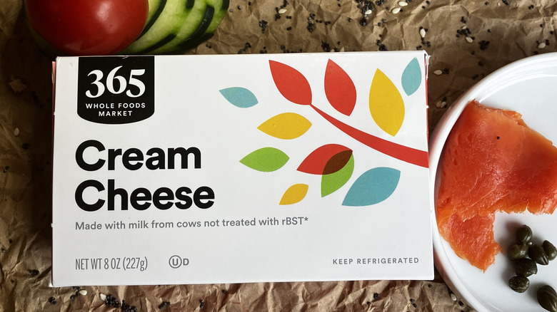 close up top view of colorful Whole Foods 365 cream cheese package with various bagel toppings surrounding it