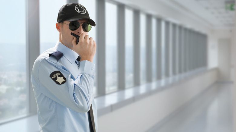 A uniformed security guard speaking into walkie talkie
