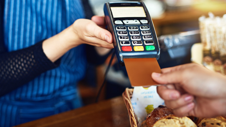 A close-up of a person inserting a credit card into the reader at checkout