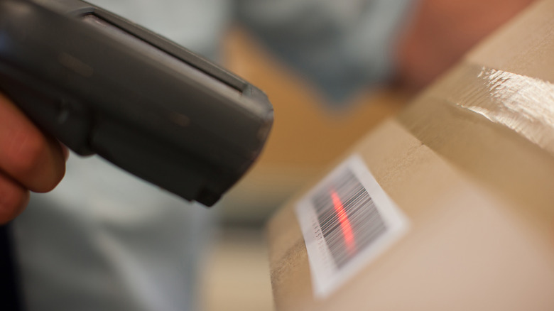 A close up of a bar code scanner scanning a barcode on a cardboard box