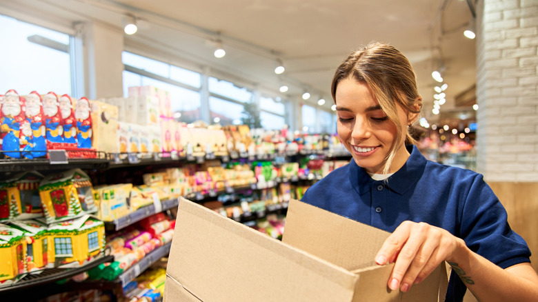 A female employee holding a box in the grocery aisle