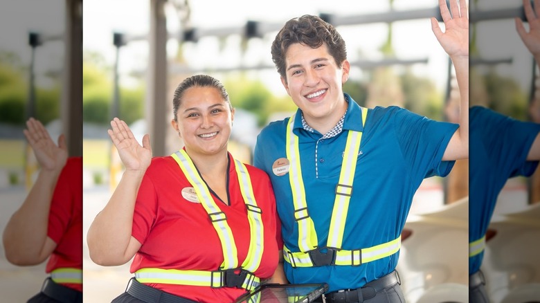 Two waving, smiling Chick-fil-A employees