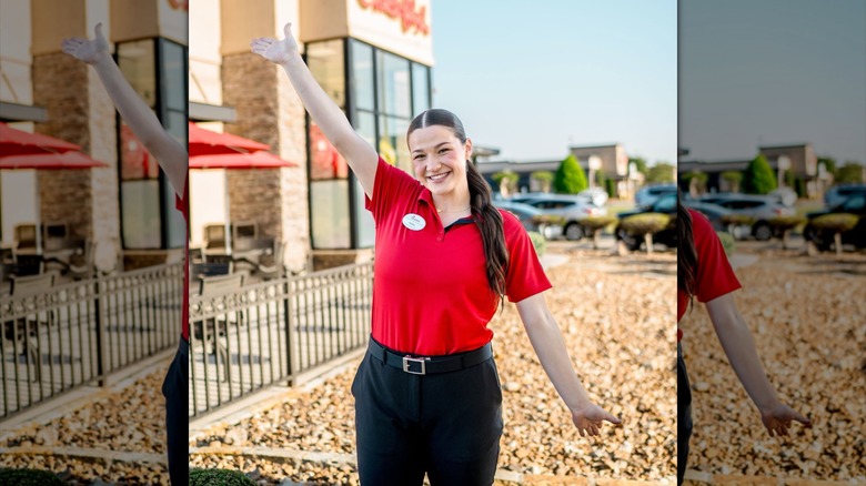 Smiling Chick-fil-A employee in red shirt and black pants