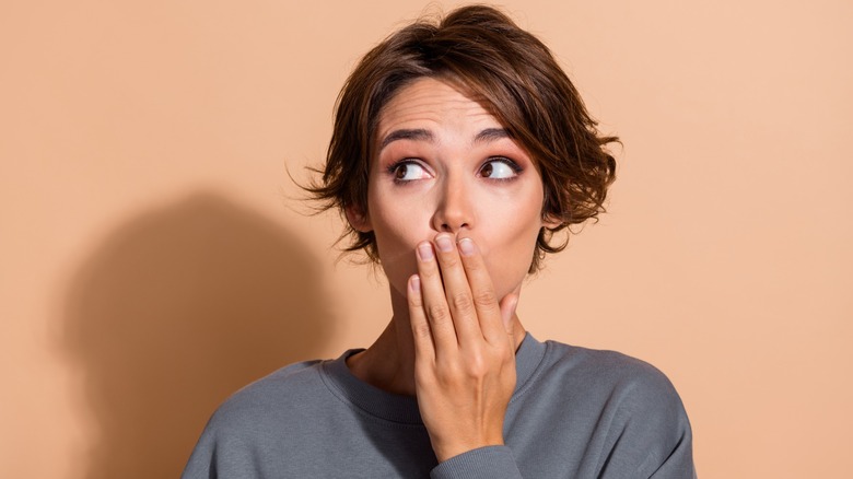 A lady covering her mouth looking shocked because of a mistake