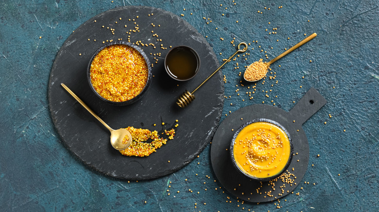 Bowls of honey and Dijon mustard on a black background