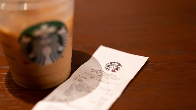 Receipt of Starbucks coffee and blurred plastic cup as background