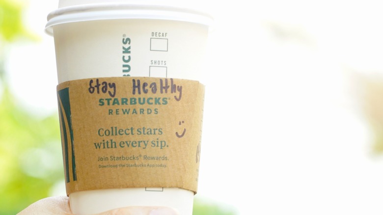 Starbucks cup with "Stay Healthy" handwritten on it and a smily face