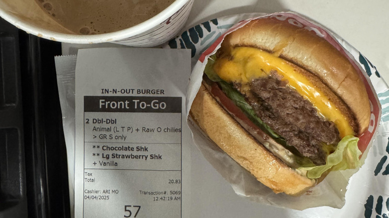 A view of a In-N-Out burger, and chocolate shake with no lid. The receipt sits face-up in the middle.