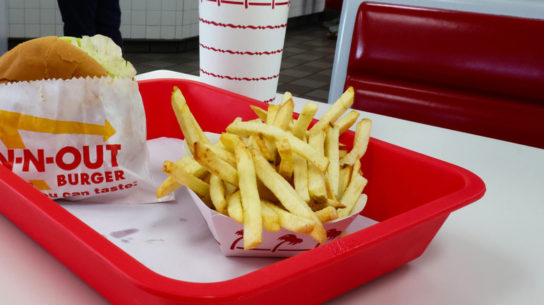 A package of fries from In-N-Out, resting in a red tray. A burger sits to the left.