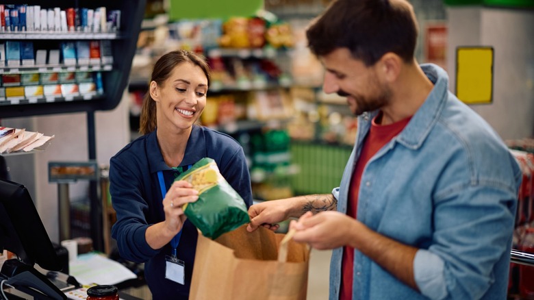 An employee helping customer bag groceries