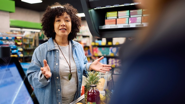 Supermarket customer communicating with cashier while paying for groceries at cash register