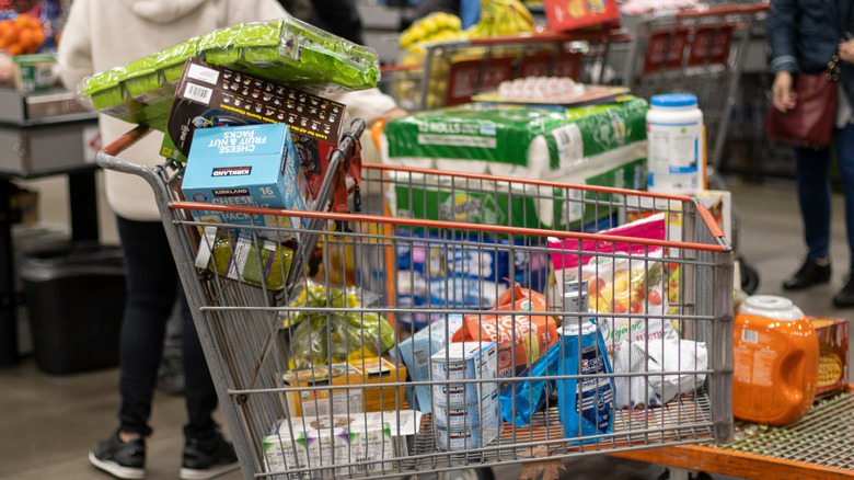 A close up of a shopping cart. The front of the cart is piled high with bulk items.