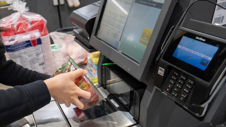 A self-checkout counter at Costco. The customer is scanning a package of strawberries.