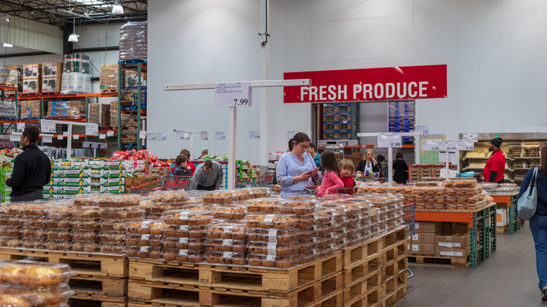 A Costco bakery and produce section where bulk packages of muffins and other pasteries are stacked.