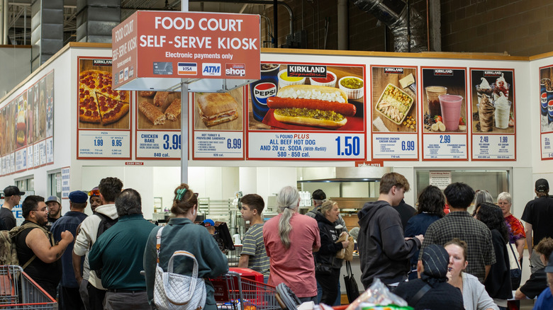 A crowded Costco foodcourt. Pictures of the signature offerings are posted overhead.