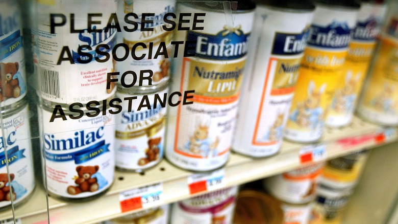 Cans of powdered baby formula are seen locked behind glass on shelves at a store