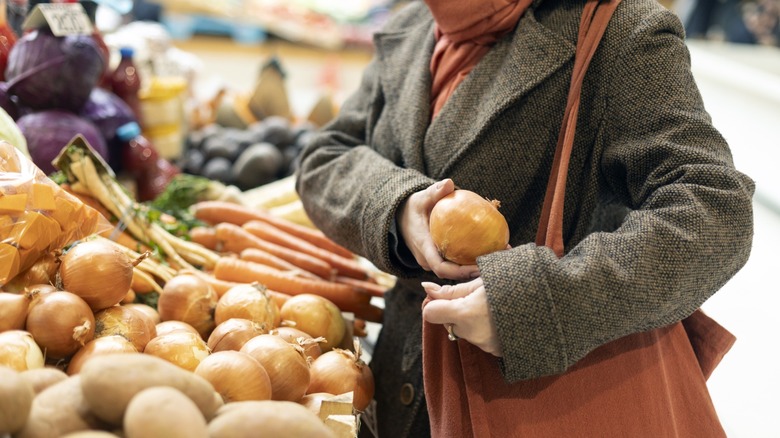woman stealing fresh produce, onion, from grocery store