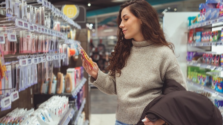 Young woman shopper holding a packet of razor blades at store