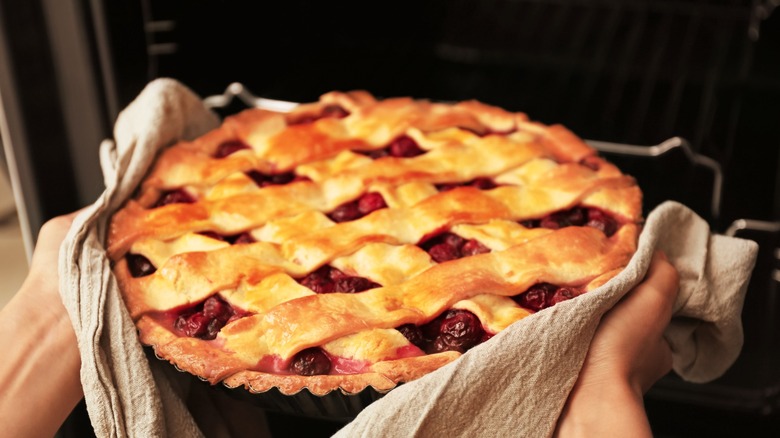 taking freshly baked cherry pie out of oven