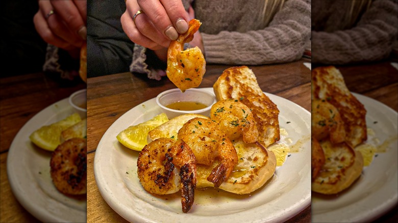 Hand holding piece Texas Roadhouse Sidekick Shrimp, dipped in sauce