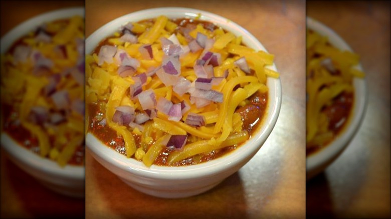 Bowl of Texas Roadhouse chili, topped with shredded cheese and onion