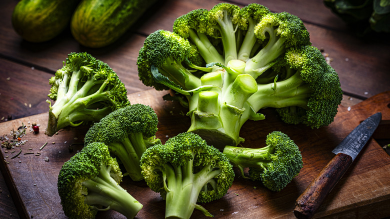 Pieces of broccoli on a chopping board, next to a knife