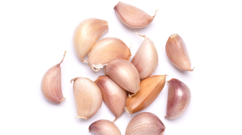 Several unpeeled garlic cloves on a white background