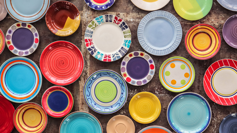 A variety of plates in different colors resting on a table.