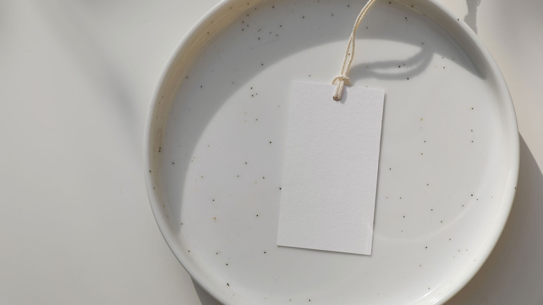 A white plate with a blank white price tag resting on it.