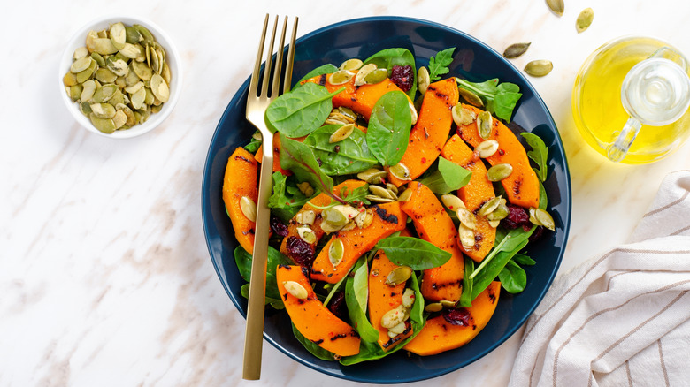 Grilled pumpkin salad with arugula, spinach, and pumpkin seed