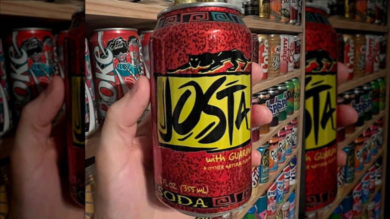 Hand holds Josta Pepsi can in front of rows of other vintage soda cans
