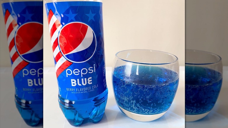 Plastic bottle of Pepsi blue next to glass of fizzy blue soda