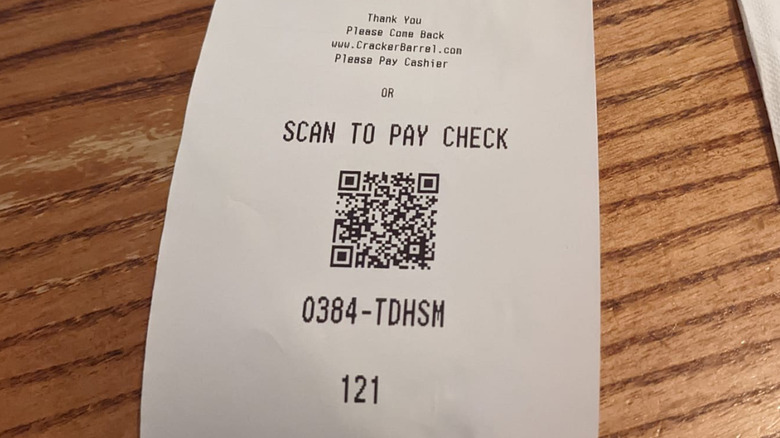 A a close up of a Cracker Barrel receipt on a wooden table, showing the scan to pay option QR code at the bottom