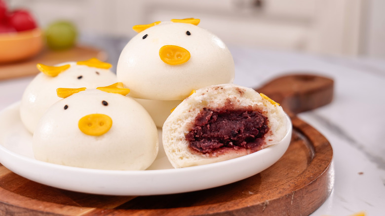Cute pig-shaped steamed buns, one cut open to reveal a red bean paste filling