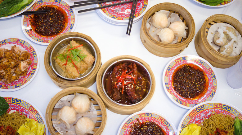 A feast of Chinese dim sum and noodles spread across a white table