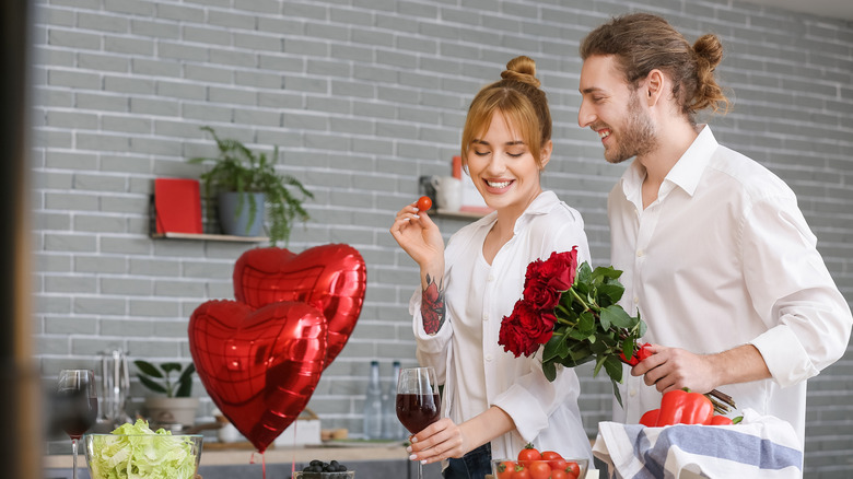 Young couple celebrating Valentine's Day while cooking festive dinner at home