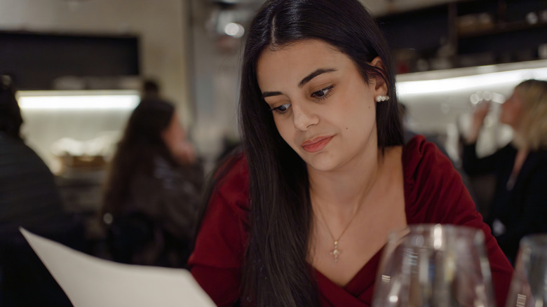 Woman in a red dress reading a menu at a restaurant
